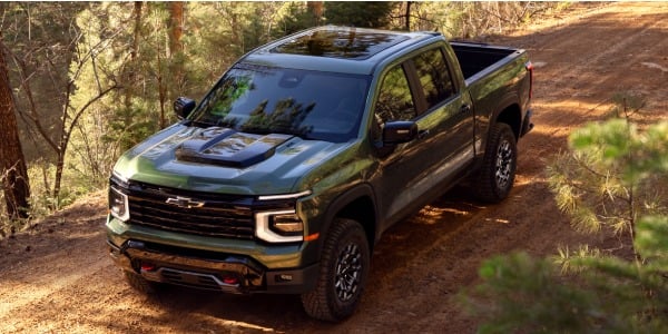 Green 2027 Chevrolet Silverado 1500 Trail Boss on a wooded off-road trail
