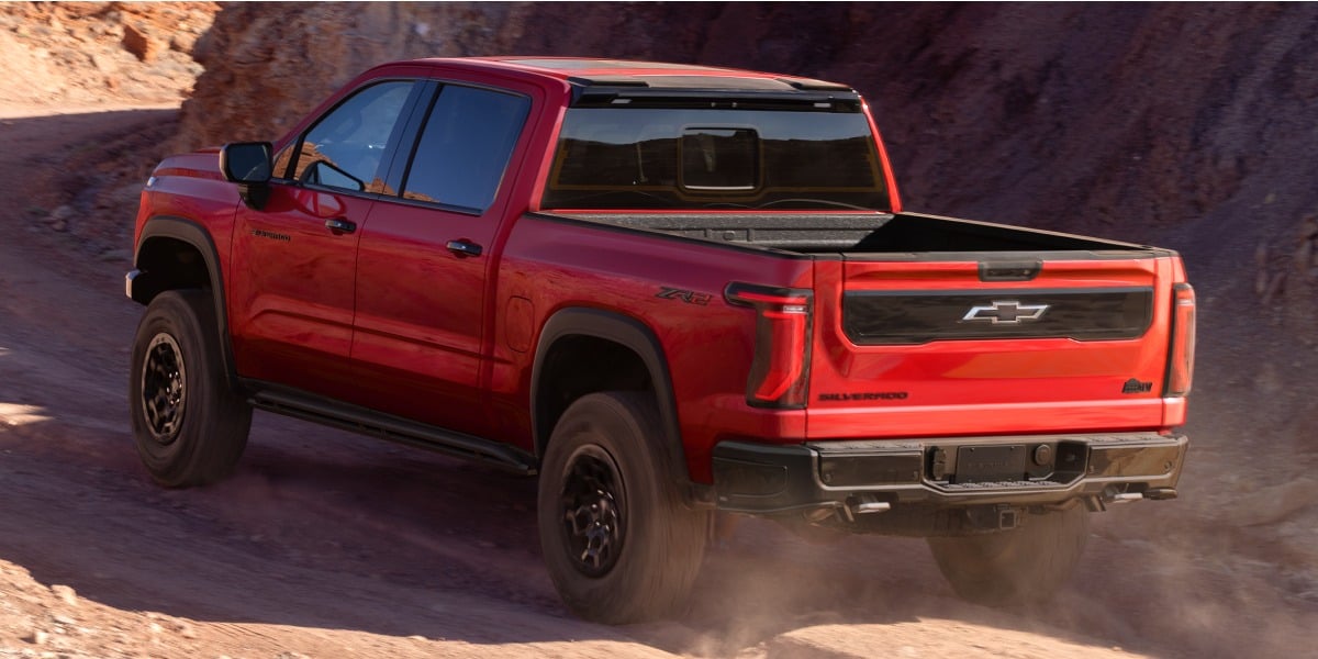 Red 2027 Chevrolet Silverado 1500 ZR2 driving off-road through a desert canyon