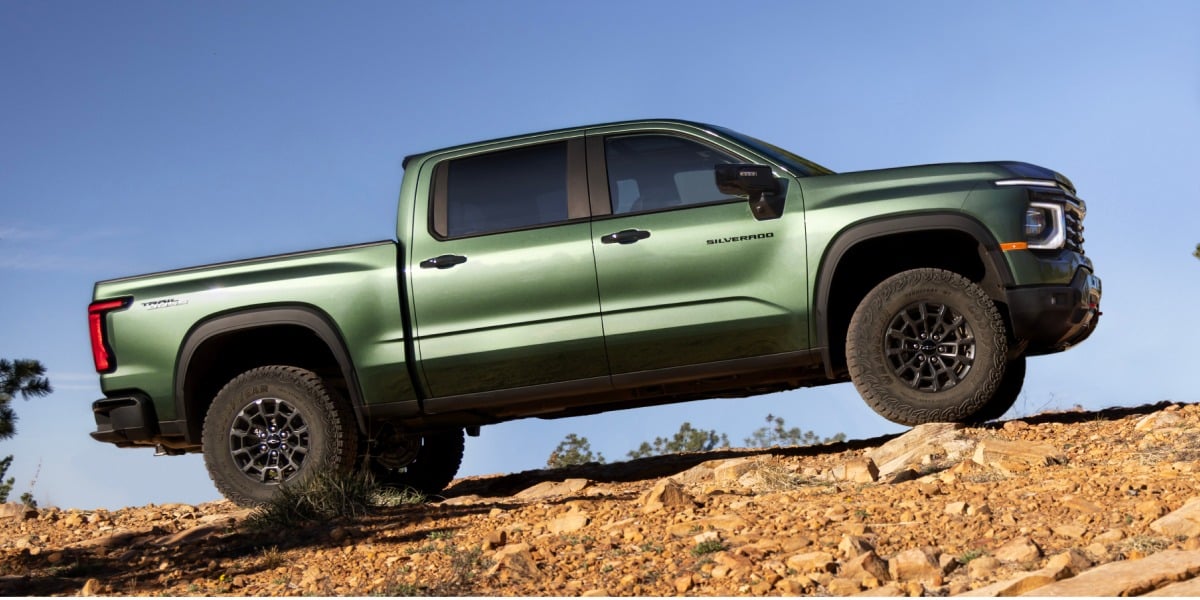 Green 2027 Chevrolet Silverado 1500 Trail Boss off-roading on a rocky hill
