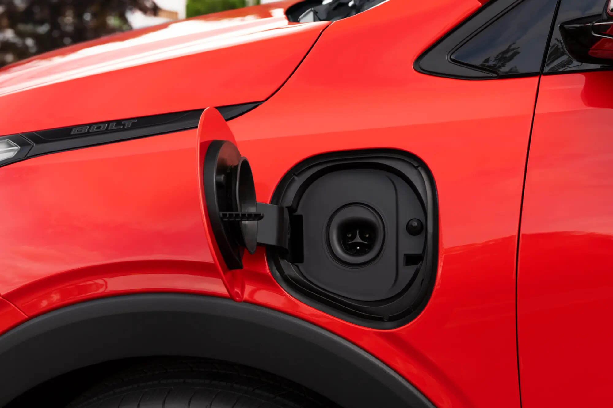 Open charge port on a red Chevrolet Bolt