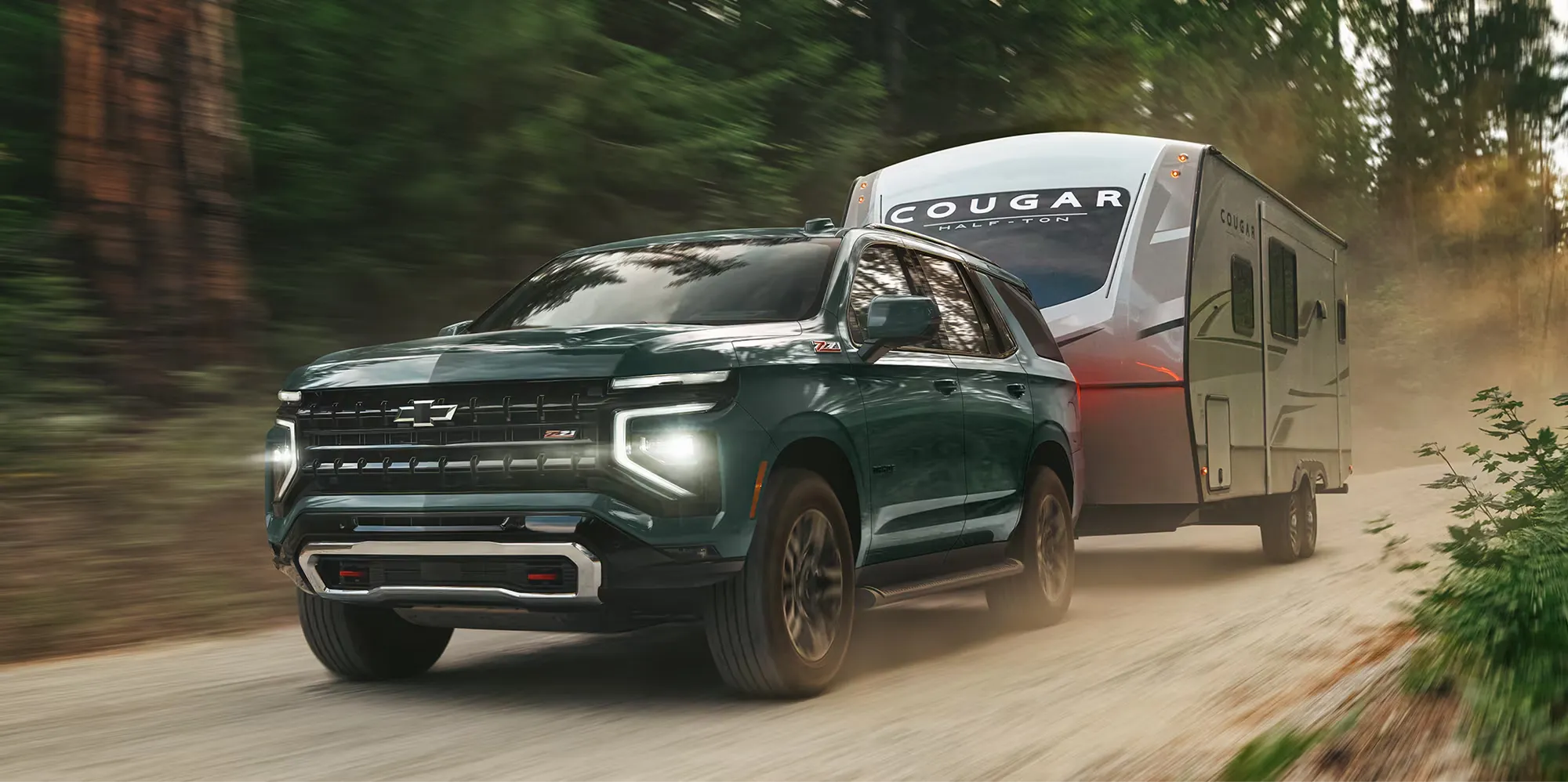 Chevrolet Tahoe 2026 remorquant une roulotte sur un chemin forestier.