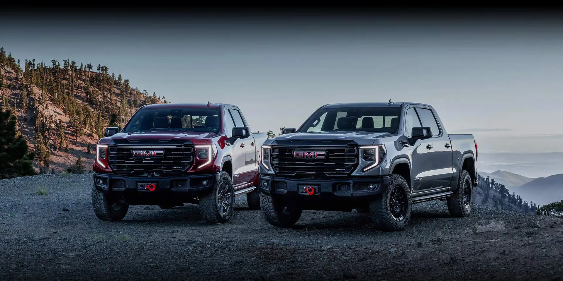 Deux versions du GMC Sierra 1500 2027 dans un décor montagneux.