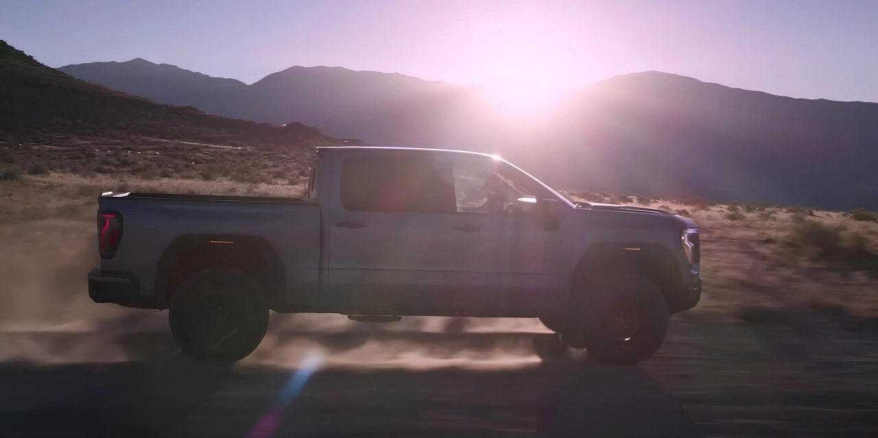 GMC Sierra 1500 2027 roulant sur un chemin au coucher du soleil.