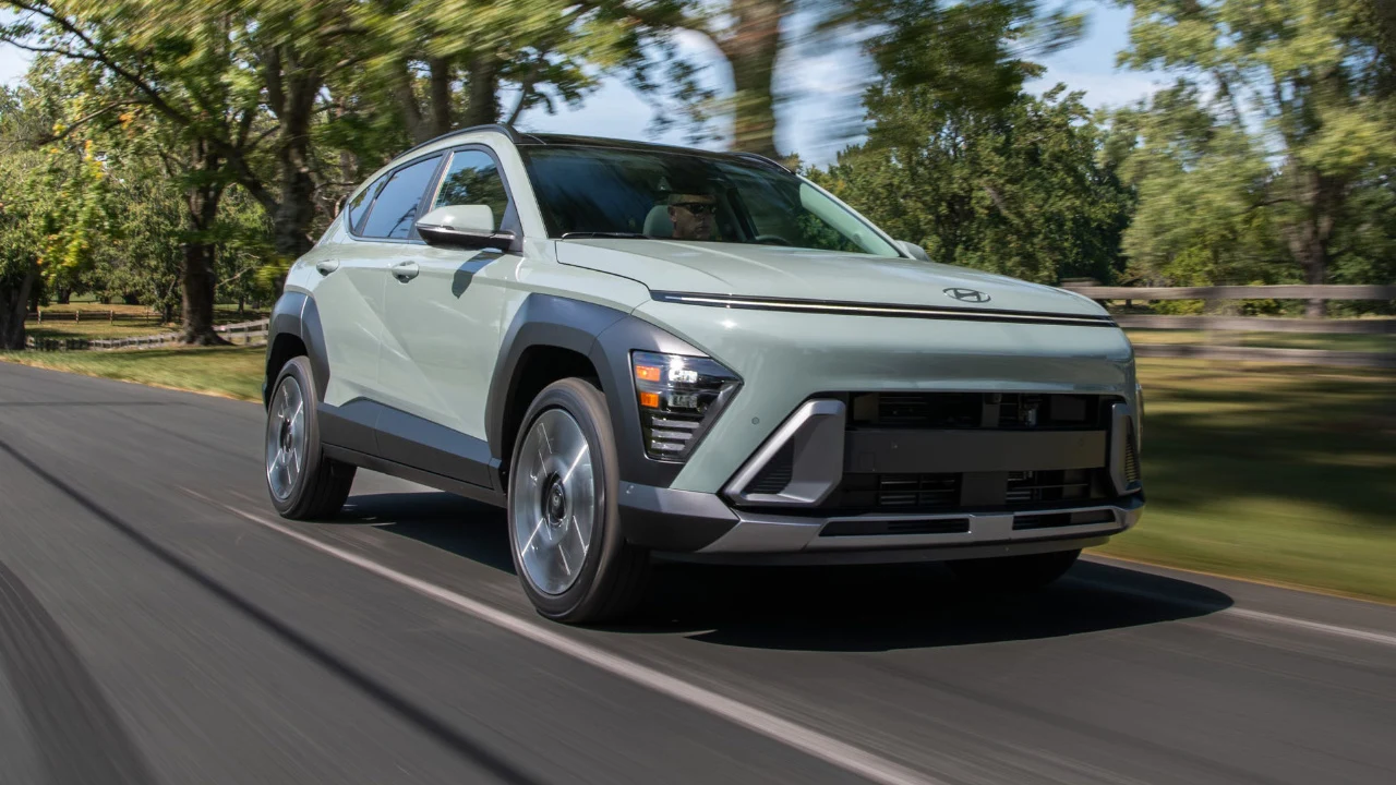 Hyundai Kona 2026 gris circulant sur une route bordée d’arbres.