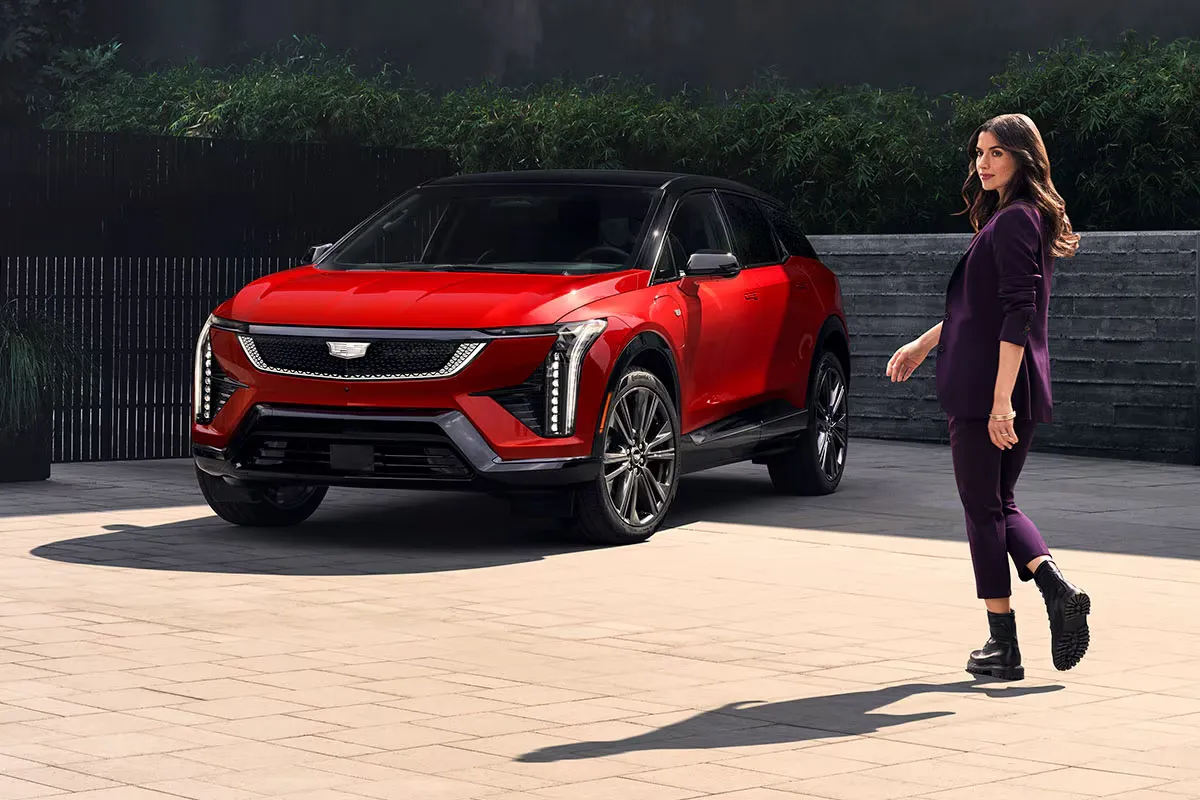 Cadillac Optiq rouge stationné devant une femme.