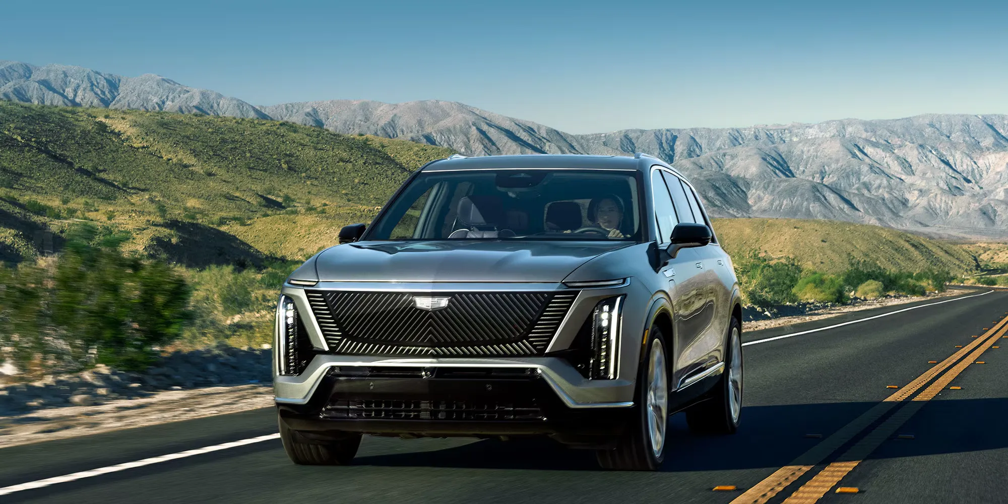 Cadillac Vistiq 2027 roulant sur une route de montagne.